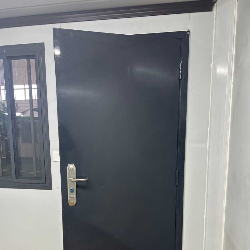 Internal electrical setup of a folding container house featuring a ceiling-mounted circuit breaker box and a white wall power outlet on insulated panels.