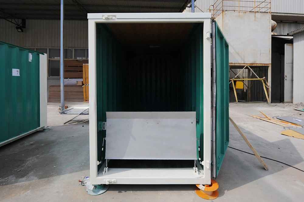 Reihe tealgrüner und weißer Motorrad-Lagercontainer auf dem Betriebshof, mit Schwerpunkt auf einer Einheit mit grüner Wellpapptür, weißen Rändern und orangefarbenen Bodenstützen für die stabile Lagerung von Motorrädern im Freien