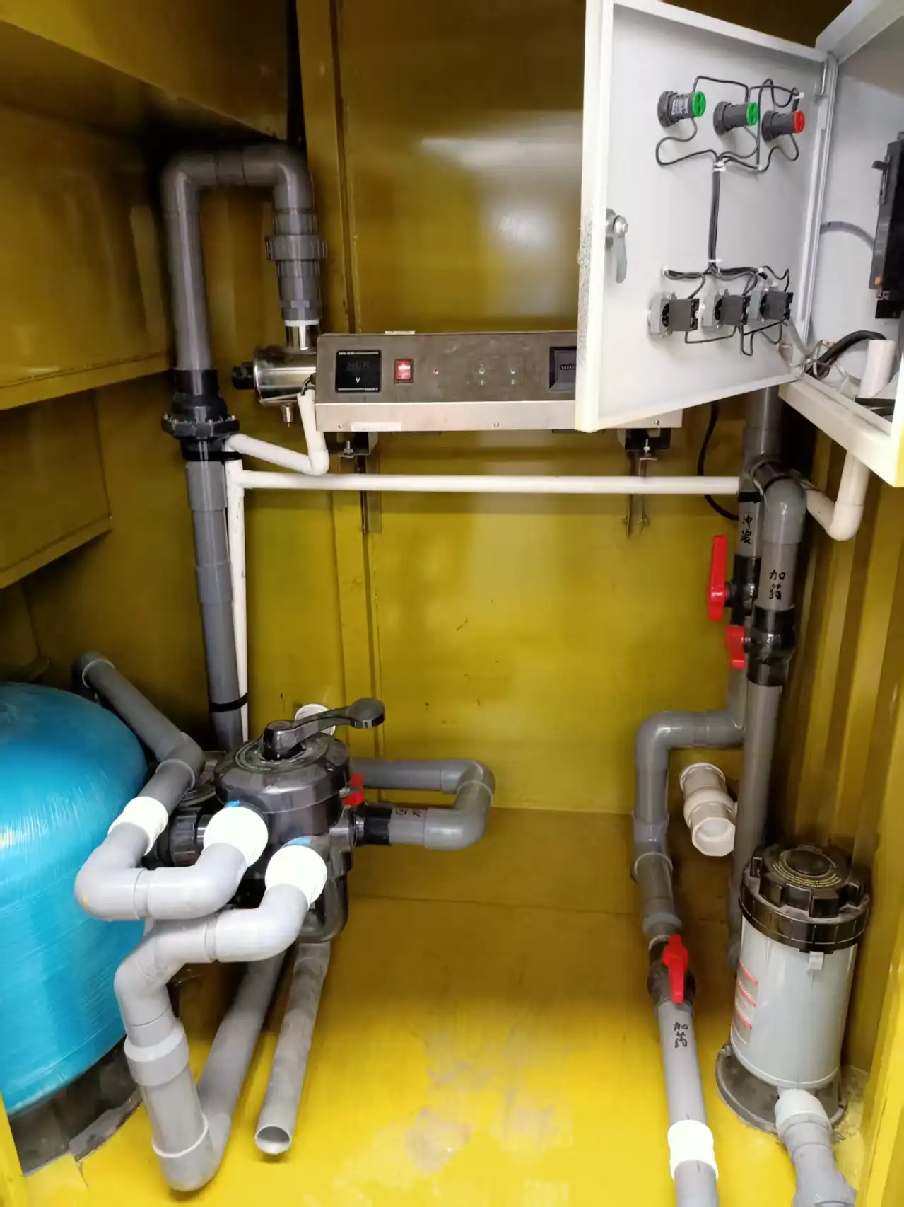 A professional interior view of the dedicated equipment room for a container swimming pool, showcasing the integrated sand filter, PVC plumbing with shut-off valves, and a centralized electrical control panel for temperature and pump management.