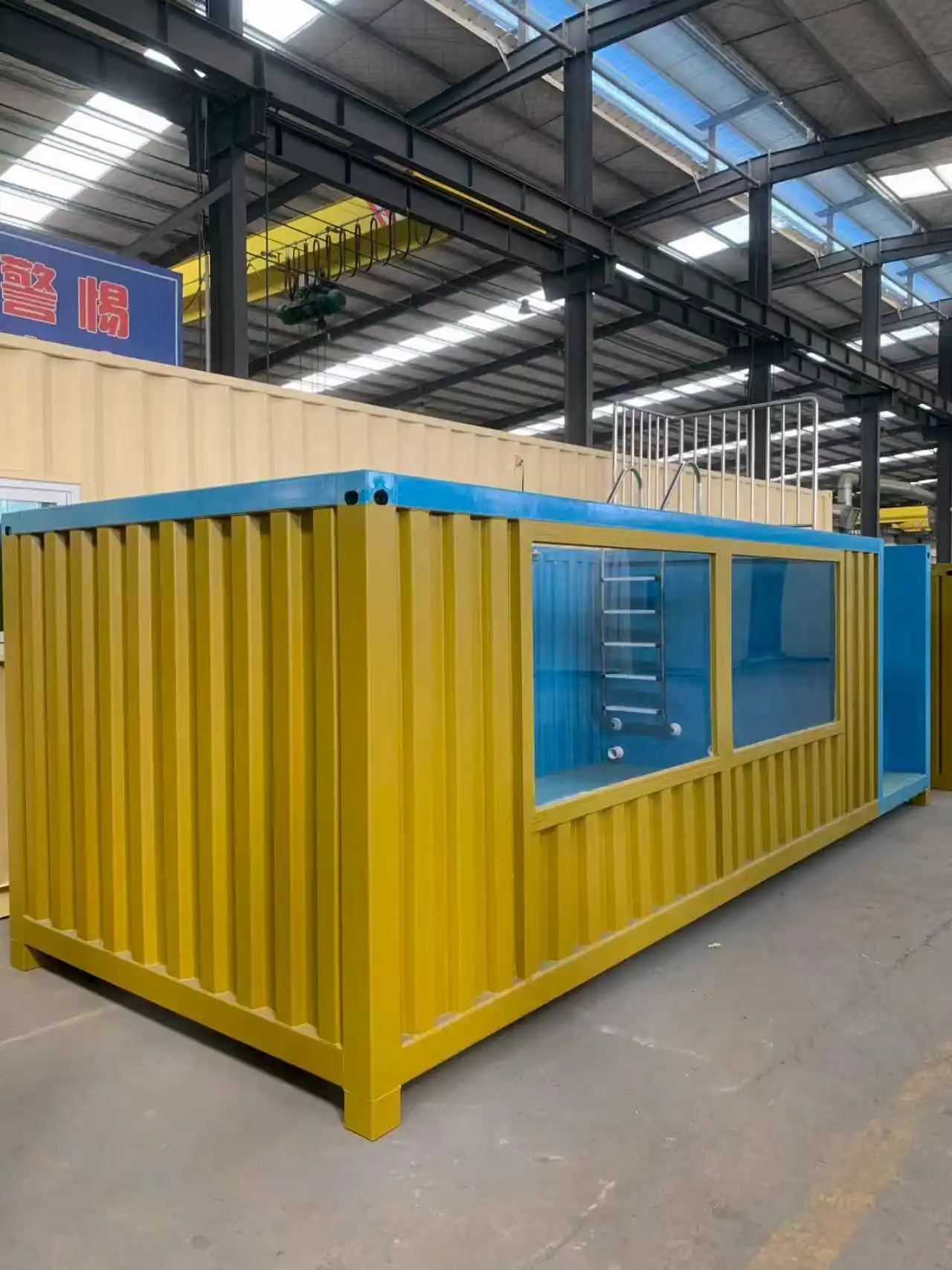 A vibrant yellow container swimming pool installed in a modern villa courtyard, featuring a deep blue interior, dual transparent viewing windows, and integrated blue access steps with stainless steel railings.